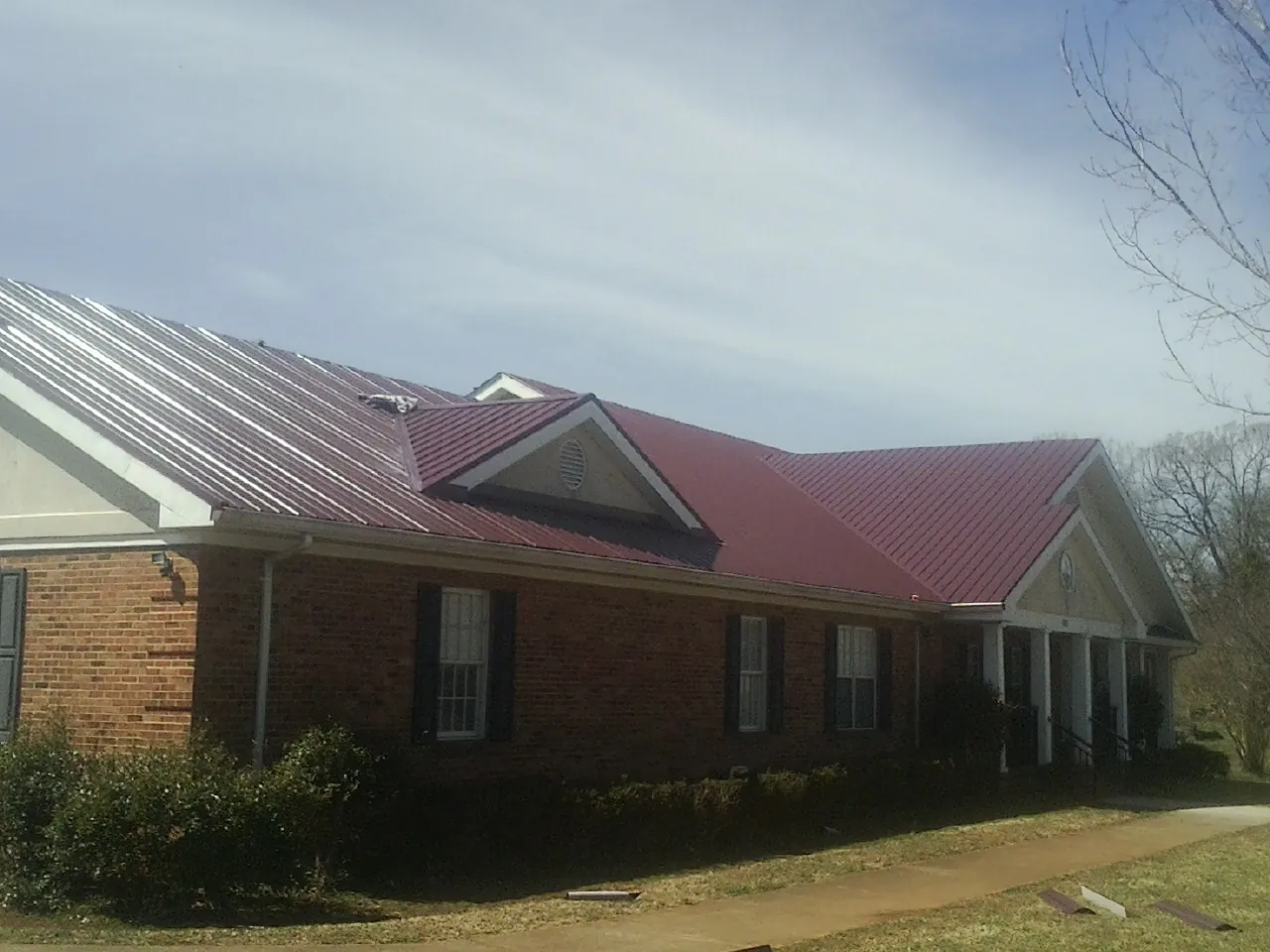 Red metal roof with gabled entries on a long brick building in Wind Ridge