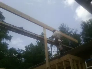 Carpenter setting a ridge beam over a new addition frame — Ice Dam Removal by Roofing Brothers in Wind Ridge