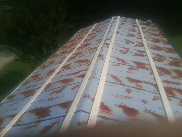 Rusted metal roof panels with new wood purlins before replacement — Storm Damage Roof Repair in Wind Ridge by Roofing Brothers