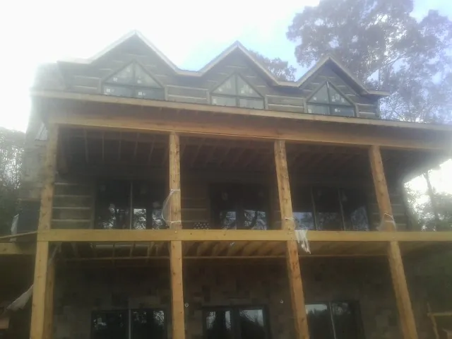 Dormers and porch framing on a large log home under construction — Roof Coating work by our crew in Wind Ridge