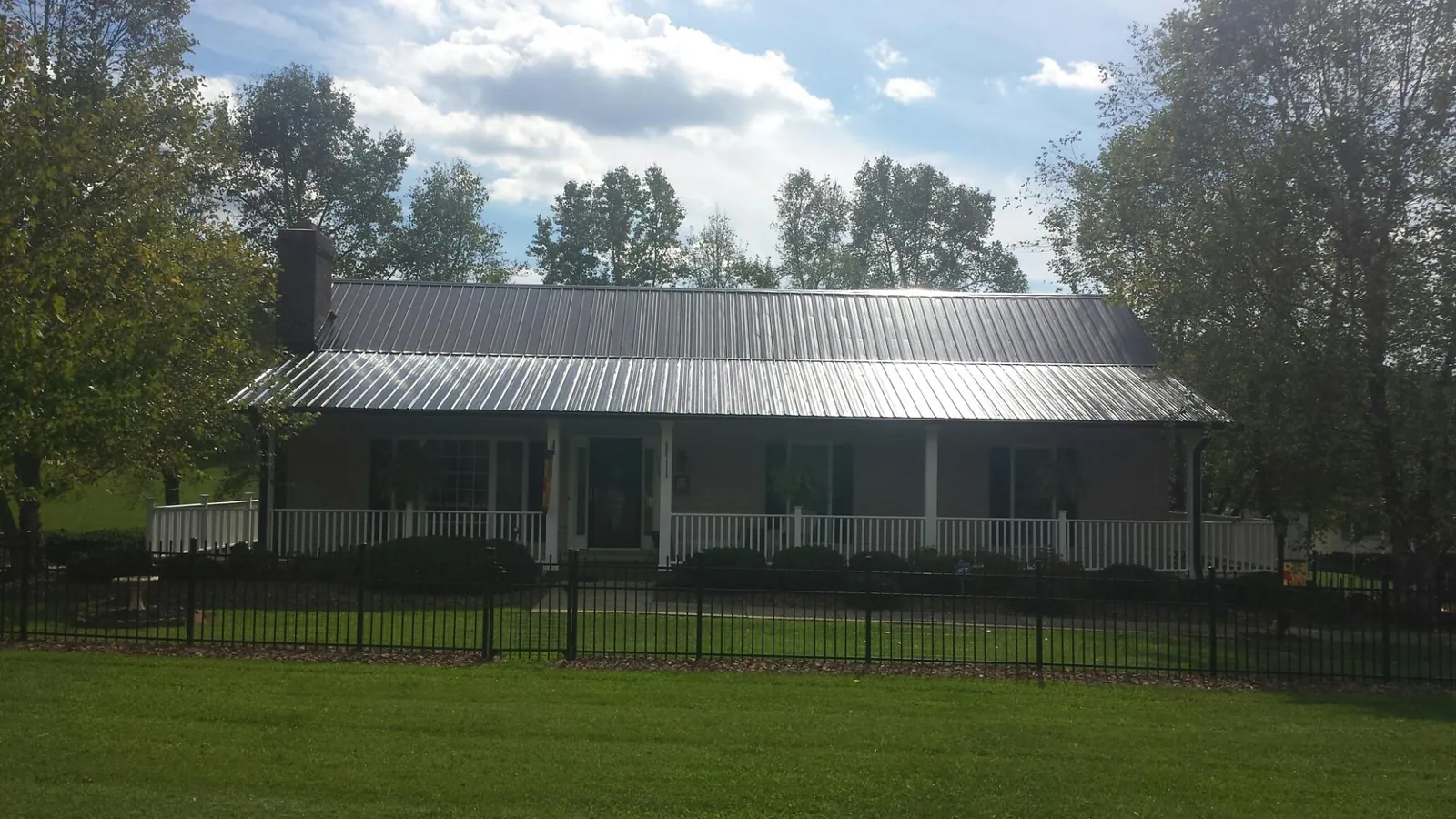 Gray metal roof on a brick ranch with a full width front porch — Gutter Guard Installation work by our crew in Wind Ridge