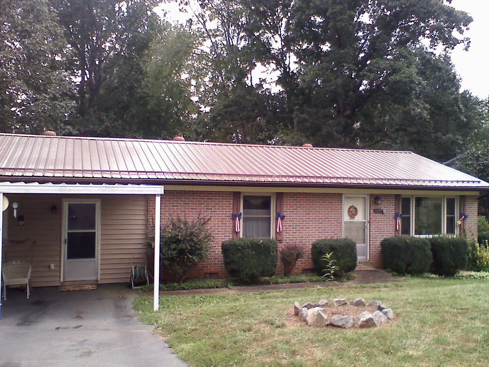 Bronze metal roof and carport on a brick ranch home — Roof Repair work by our crew in Wind Ridge