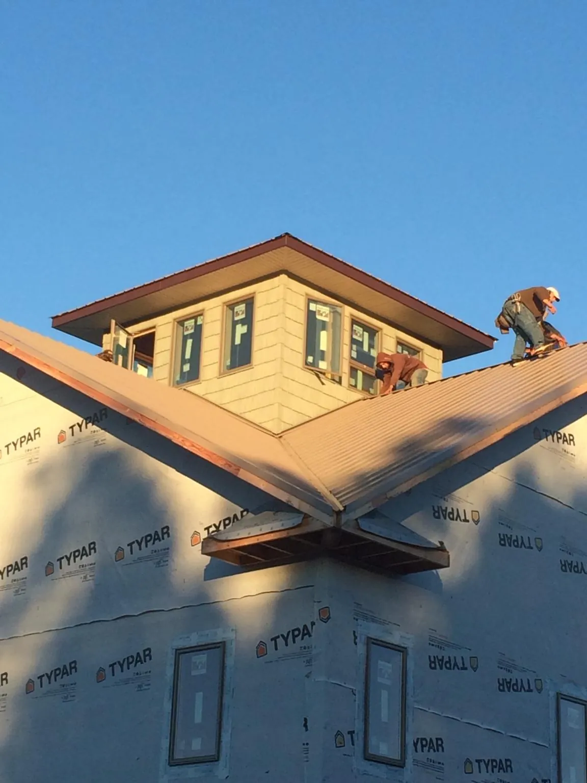 Roofers working around a rooftop cupola on a new metal roof at sunset — Roof Waterproofing in Wind Ridge by Roofing Brothers